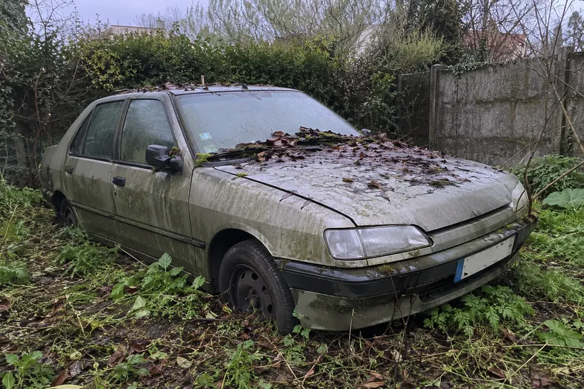 Voiture non roulante abandonnée dans un jardin, pneus à plat