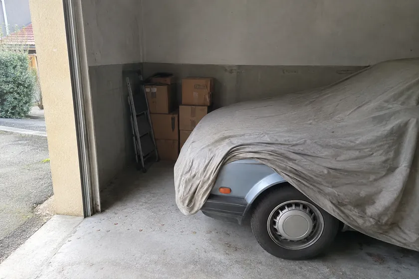 Voiture sous housse dans un box de garage fermé